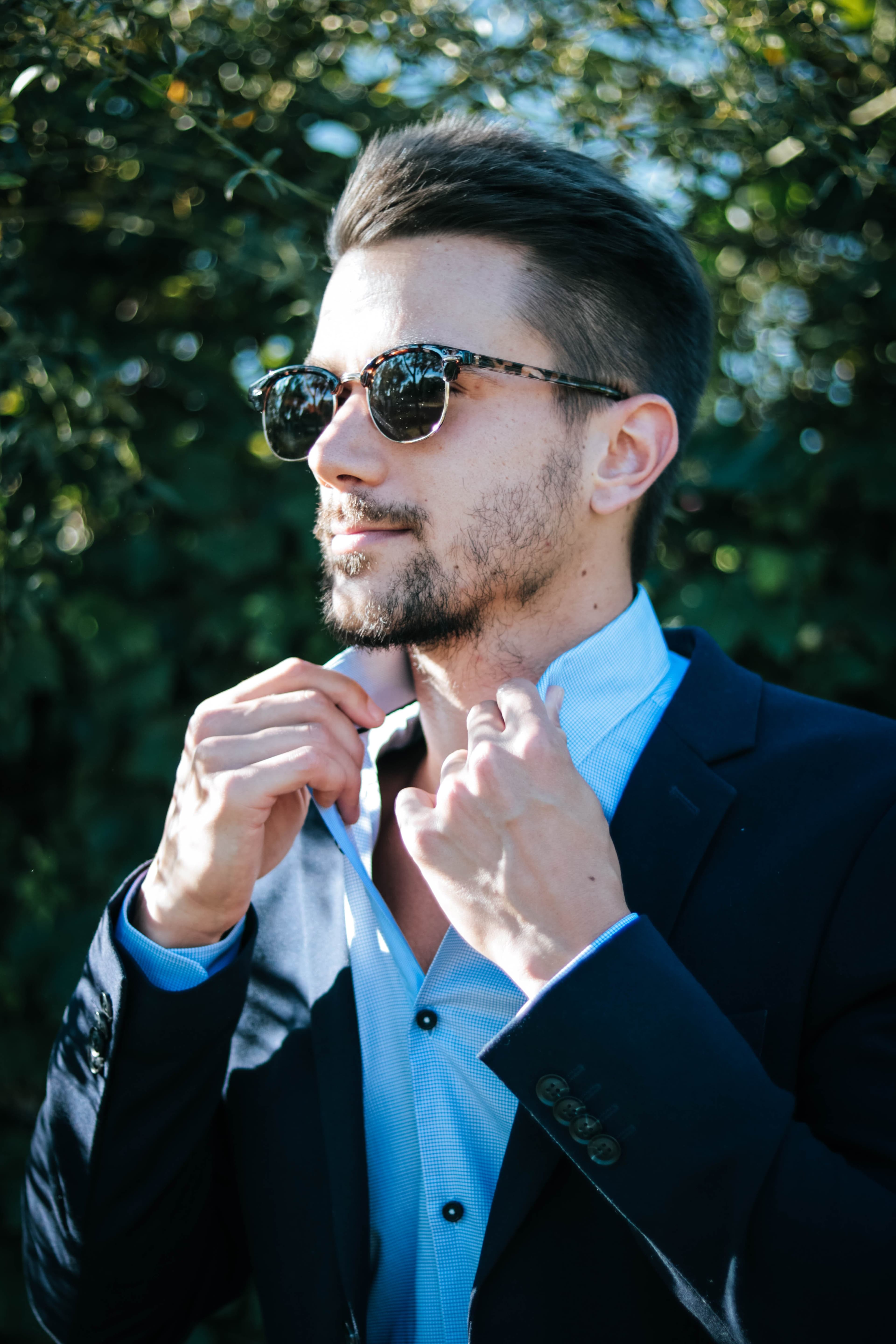 Man with glasses holding his shirt collar